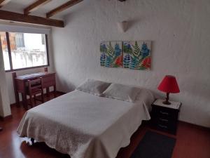 1 dormitorio con 1 cama y 1 mesa con lámpara roja en Casa Turística Camitas Inn, en Bogotá