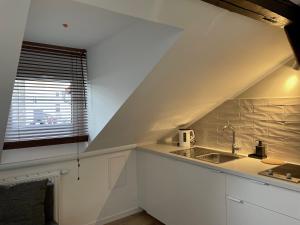 a white kitchen with a sink and a window at Apartamenty Delecta in Krakow +125 photos