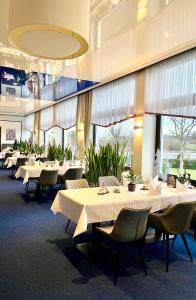 un comedor con mesas y sillas blancas en Pfefferhöhe Hotel & Restaurant, en Alsfeld