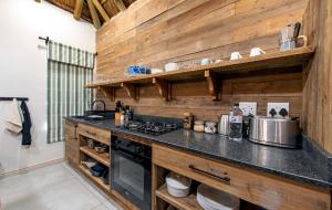 a kitchen with wooden walls and a stove top oven at Burlington Bush Cottages by The Oyster Collection in Salem