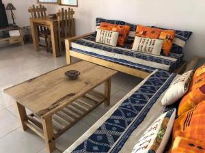 a living room with two beds and a wooden table at Maison Aziz - Somone - Sénégal in Somone