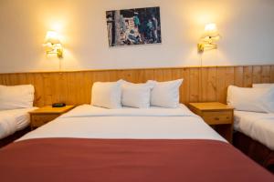 2 Betten in einem Zimmer mit 2 Lampen an der Wand in der Unterkunft Canadas Best Value Inn- Riverview Hotel in Whitehorse