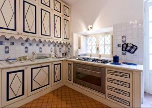 uma cozinha com armários brancos e um forno com placa de fogão em VILLA MIMOSA Taormina Rooftop Terrace em Taormina