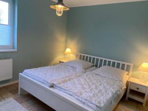 ein Schlafzimmer mit einem weißen Bett und zwei Nachttischen in der Unterkunft Nordseejuwel in Friedrichskoog-Spitze