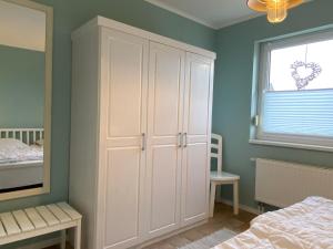 ein Schlafzimmer mit einem weißen Schrank und einem Bett in der Unterkunft Nordseejuwel in Friedrichskoog-Spitze