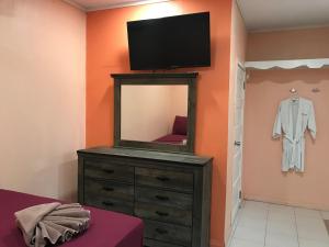 a bedroom with a dresser with a mirror and a tv at Tropical Paradise in Caye Caulker