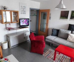 uma sala de estar com uma cadeira vermelha e um sofá em Fewo 91 WHG B 15 in Burhave em Burhave