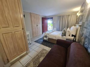 a bedroom with a bed and a couch in front of a door at THE THATCH HIDE in East London