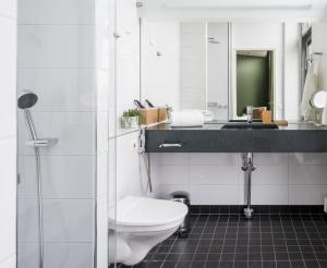 a bathroom with a toilet and a sink and a mirror at Hiisi Hotel Helsinki Jätkäsaari in Helsinki