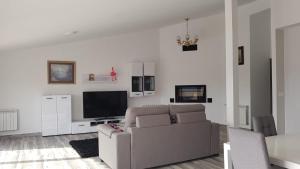 a living room with a couch and a flat screen tv at Apartamentos Las Huertas in Villamiel
