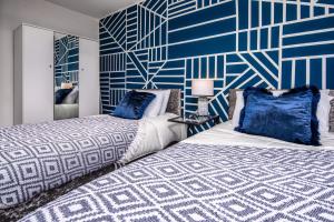 two beds in a bedroom with a blue and white wall at Long Term Stays Check Exclusive Rates - www,cosy-spaces,c o,uk in Leeds