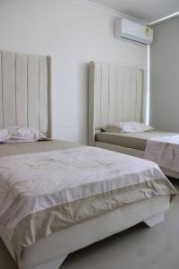 1 Schlafzimmer mit 2 Betten in einem weißen Zimmer in der Unterkunft Hermosa Casa Grande De 3 Pisos Barranquilla in Barranquilla