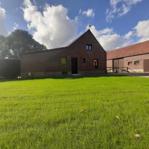 a large grass field in front of a brick building at Het Innerhof in Oudsbergen 