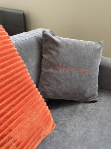 un oreiller orange sur un canapé avec un oreiller gris avec les mots ne pas se tromper dans l'établissement "C'est la Récré" Place de parking privative Centre ville, à Dieppe
