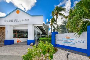 a building with a sign that reads blue village at Aruba Blue Village Hotel and Apartments in Palm-Eagle Beach