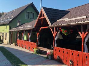 a house with a red fence in front of it at Tünde Vendégház in Viştea