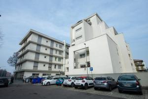 a white building with cars parked in a parking lot at Appartamenti Maggiore Parma in Parma