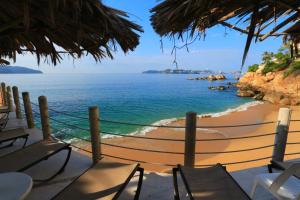 een uitzicht op een strand met stoelen en een net bij Suites Torres Gemelas VIP in Acapulco