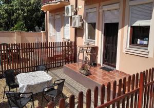 a patio with a table and chairs and a fence at Hellasz Apartman in Gyula
