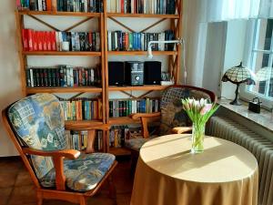 ein Zimmer mit einem Tisch, 2 Stühlen und einem Bücherregal in der Unterkunft Terraced house, Nessmersiel in Neßmersiel