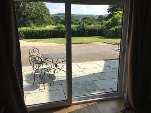 an open door with a table and chairs on a patio at Bond End Road Annex Upton St Leonards - Ideal for Cheltenham Races in Matson