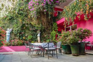 a table and chairs in front of a pink wall with flowers at Casa de las Bugambilias B&B in Oaxaca City