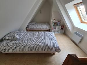 a bedroom with a bed and two stools in a attic at Maison 2 pas du centre ville et proche plage in Courseulles-sur-Mer