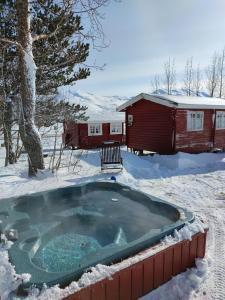a hot tub in the snow next to a cabin at Dalvík Vegamót Cottages in Dalvík