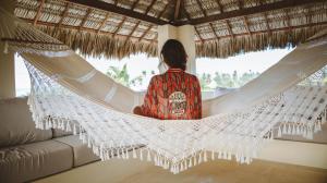 a person sitting in a hammock in a house at Avra Tatajuba in Tatajuba