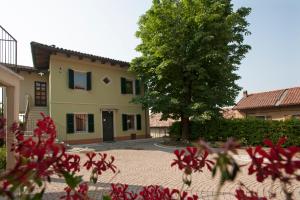 una casa con un albero e fiori rossi in primo piano di Casa Brina Suites a Cocconato