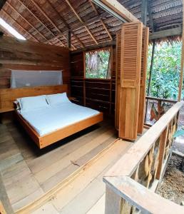 1 dormitorio con 1 cama en una terraza de madera en Casa Azul Reserva Amazonica, en Leticia