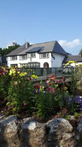 een wit huis met bloemen ervoor bij Ryan's River Lodge B&B in Cong