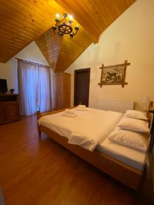 Un dormitorio con una cama con sábanas blancas y una lámpara de araña. en Hasienda en Rîşnov