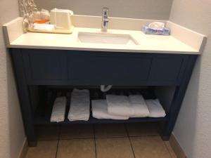 a bathroom vanity with a sink and towels under it at AmericInn by Wyndham New Braunfels in New Braunfels