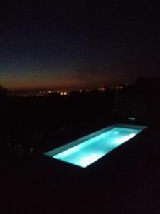 una piscina iluminada en la oscuridad por la noche en Tomažev SVET, en Zgornje Škofije