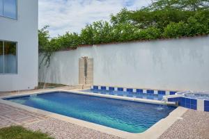 吉拉爾的住宿－Casa vacacional Girardot 5 habit，白色墙壁前的游泳池