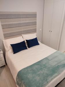 a bedroom with a large white bed with blue pillows at Estudio Madrid Norte 2 in Madrid
