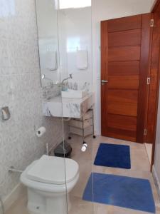 a bathroom with a toilet and a sink and a mirror at Xodó da Praia - amplo apartamento 3 qts 260 m da praia in Santa Cruz
