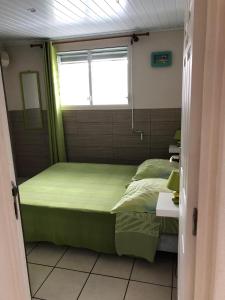 Habitación pequeña con cama y ventana en Kay Ghislaine, en Les Anses-dʼArlet