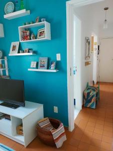 a room with a blue wall with a desk with a television at Vista&Aconchego in Santos