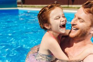 a man and a little girl in a swimming pool at Family Resort Hotel Милоо in Loo