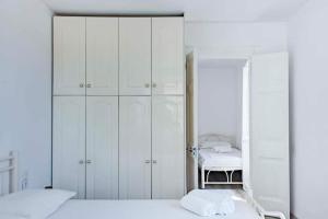 a bedroom with white cabinets and a bed with a mirror at Casa di Roza in Corfu