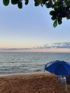 a blue umbrella and chairs on the beach at Xodó da Praia - amplo apartamento 3 qts 260 m da praia in Santa Cruz