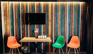 a table with three chairs and a television on a wall at Loft Hotel in Bukovel