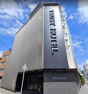 un edificio con un cartel de hotel fiduciario en él en Trust Hotel en Hiroshima