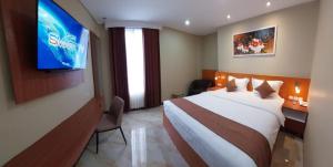 Cette chambre comprend un lit et une télévision. dans l'établissement Grand Avira Hotel, à Batu Merah
