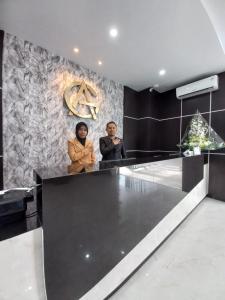 two people sitting at a counter in a lobby at Grand Avira Hotel in Batu Merah