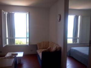 a room with a bed and a couch and two windows at Rocca Ruja Vip in Stintino