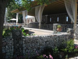 a stone wall next to a patio with tables and chairs at Philoxenia in Kalabaka