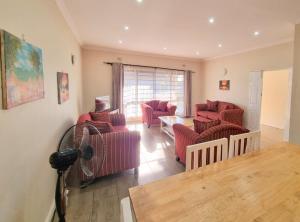 a living room with red chairs and a fan at Mwaiseni Maisonettes apartments in Ndola